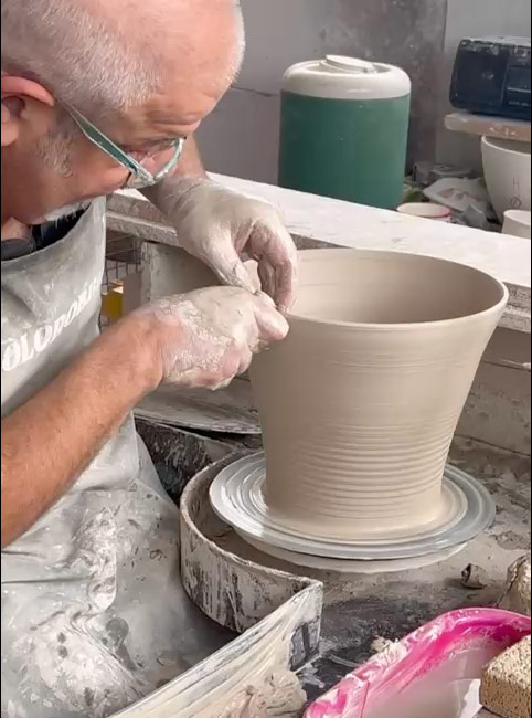 Ceramic artisan Mastrogiorgio in Umbria working a terracotta vase on a potter's wheel, traditional Italian know-how.